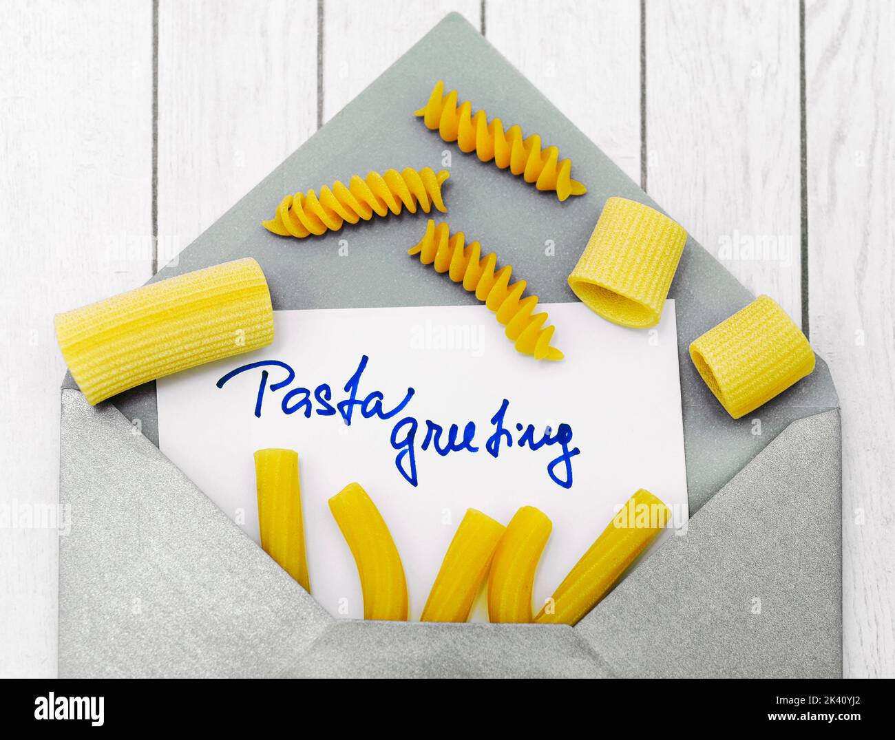 Umschlag mit Text Pasta Grüße und verschiedene Arten von rohen ungekochte Pasta auf weißem Holz Hintergrund wie grafische Konzept von Pasta-Essen Stockfoto