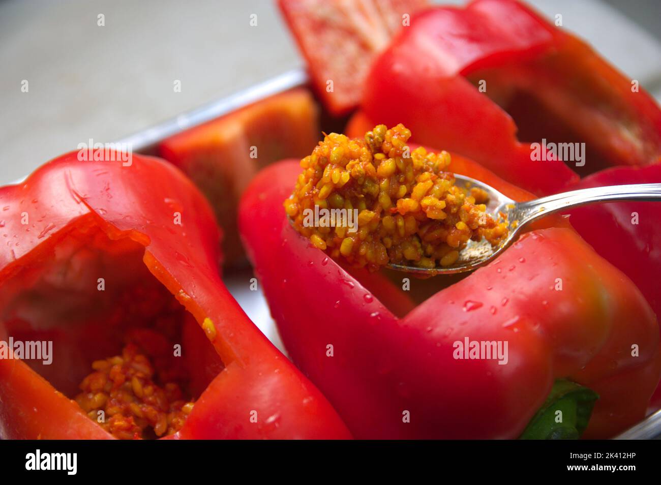 Nahaufnahme eines Löffels voller Reis, zubereitet mit Tomaten und Fleisch, das in einem roten Pfeffer gekocht werden soll Stockfoto