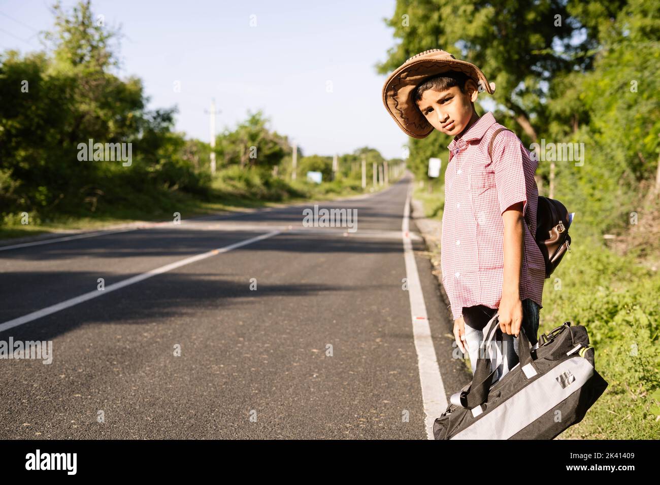 Teenager indisches Kind wartet auf Bus oder Taxi auf der Autobahn Straße während der Urlaubsreise - Konzept der Reise, Wochenendferien und Liesure Lifestyle. Stockfoto