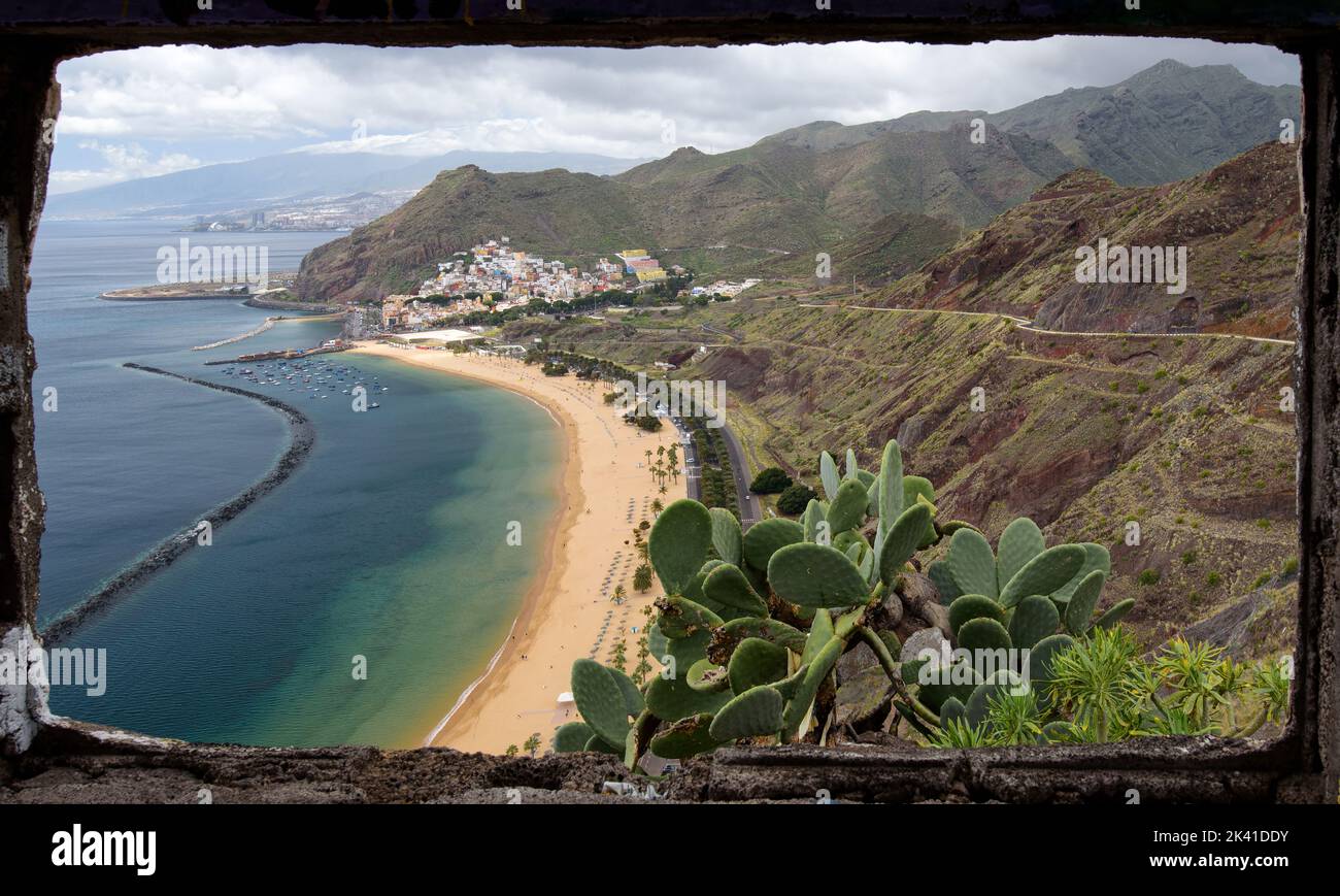 Der künstliche, weiße Sand, Touristenstrand der Playa de Las Teresitas, vom Mirador aus gesehen, umrahmt von einem Fenster eines zerstörten Gebäudes. Stockfoto