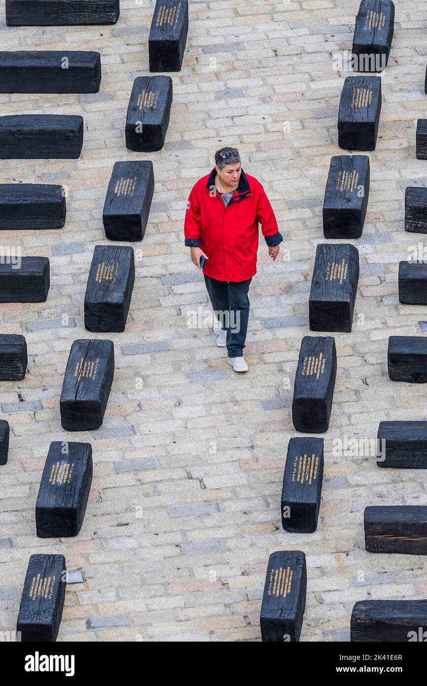 London, Großbritannien. 29. September 2022. O Barco/The Boat, eine Installation der Künstlerin Grada Kilomba, im Somerset House in London. Es ist das 10.-jährige Jubiläum der Contemporary African Art Fair 1-54. Die 32 Meter lange Installation, die aus 140 Holzblöcken besteht und die Form eines europäischen Sklavenschiffs umreißt, lenkt die Aufmerksamkeit auf die vergessenen Geschichten und Identitäten derjenigen, die während der europäischen maritimen Expansion und Kolonisierung gelitten haben. Die Blöcke, metaphorische Gräber, wurden vom Künstler verkohlt und einige mit Gedichten beschriftet. Kredit: Guy Bell/Alamy Live Nachrichten Stockfoto