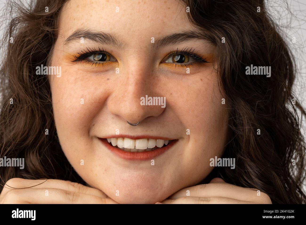 Junge Dame lächelt der Kamera zu, mit durchbohrter Nase. Stockfoto