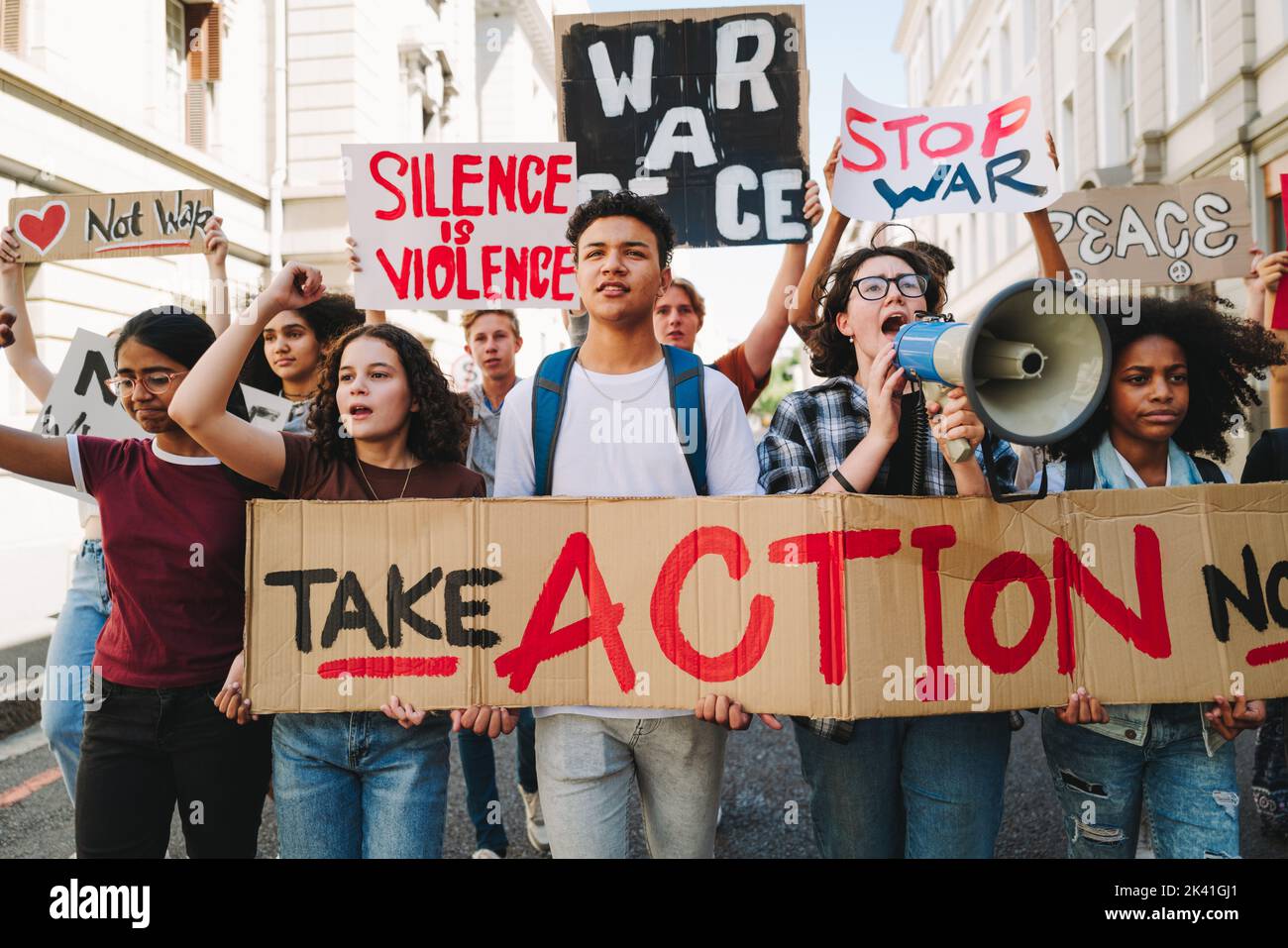 Aktivismus für Frieden und Menschenrechte. Eine Gruppe multikultureller Friedensaktivisten marschiert mit Plakaten und Spruchbändern auf die Straßen. Vielfältige junge Menschen protes Stockfoto