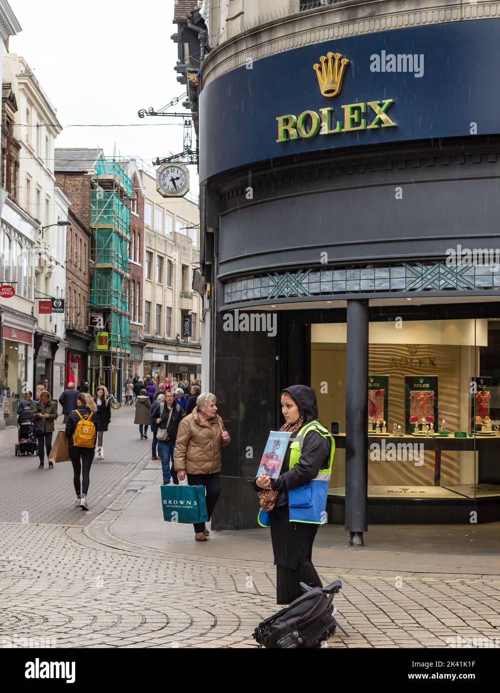 York, North Yorkshire, Großbritannien, September 29 2022. Porträt einer Verkäuferin des Big Issue Magazine stand im Regen vor einem Juweliergeschäft in York City Stockfoto