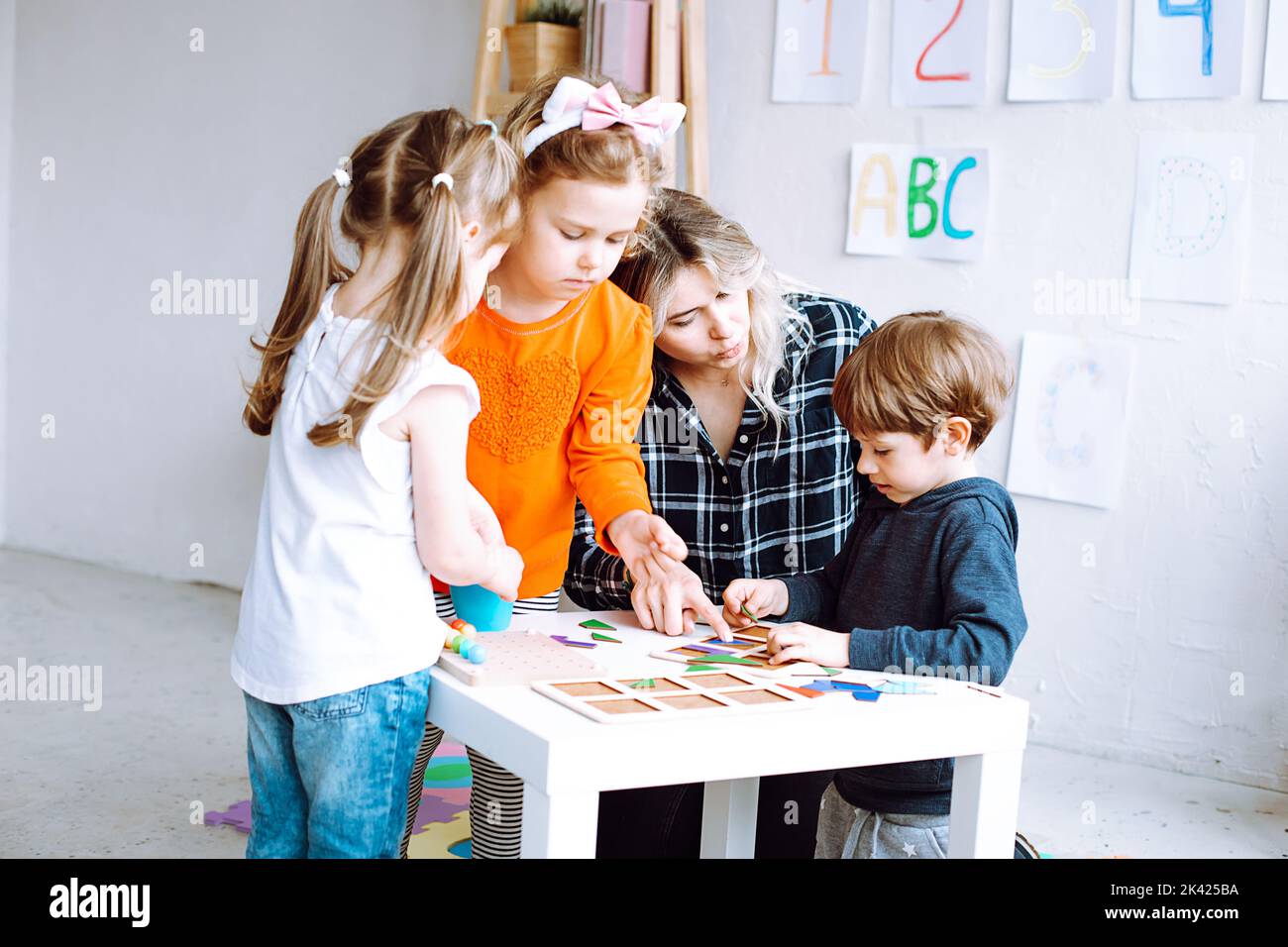 Blonde Frau, Lehrer spielen und lernen kleine Kinder, Spaß zusammen Entwicklung Kindertagesstätte. ABC, Logikklasse Stockfoto