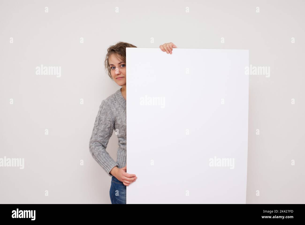 Hübsche Frau posiert hinter einem weißen Panel isoliert auf weißem Hintergrund Stock Foto Stockfoto