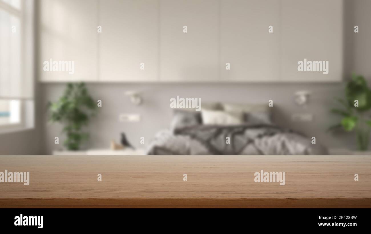 Leerer Holztisch, Schreibtisch oder Regal mit verschwommenem Blick auf das moderne, weiße Schlafzimmer, Bett mit Federdecke, Beistelltischen und Topfpflanzen, Kleiderschrank, minimalistischer Schrank Stockfoto