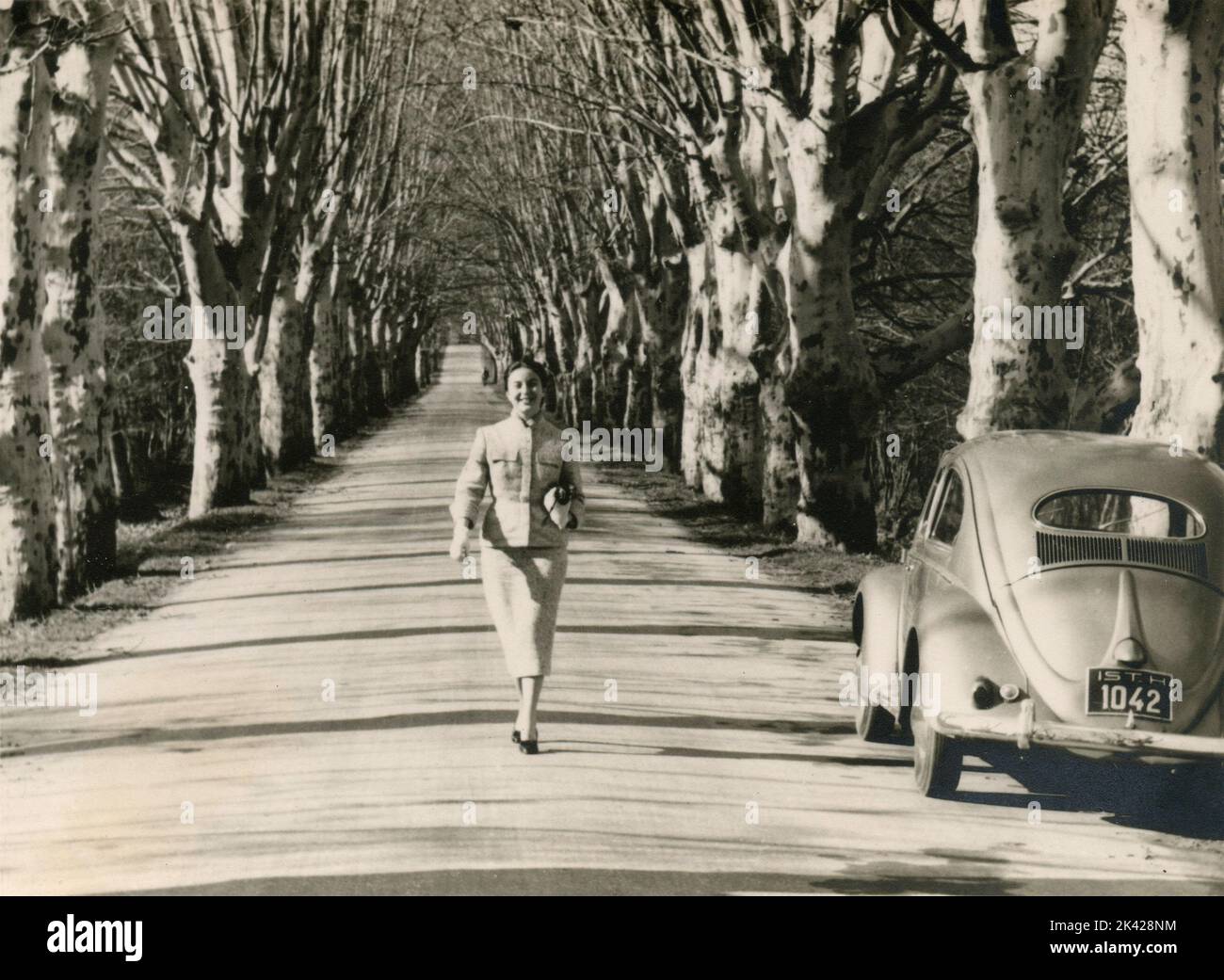 Lächelnde Frau, die in einer von Bäumen gesäumten Allee läuft, Frankreich 1955 Stockfoto