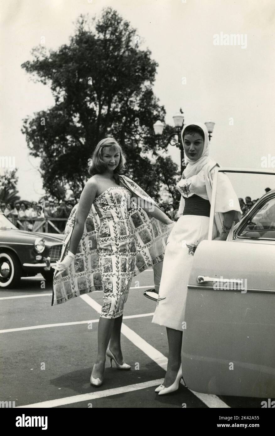 Zwei Modelle zeigen ihre Kleider neben einem Auto, Rom, Italien 1950s Stockfoto