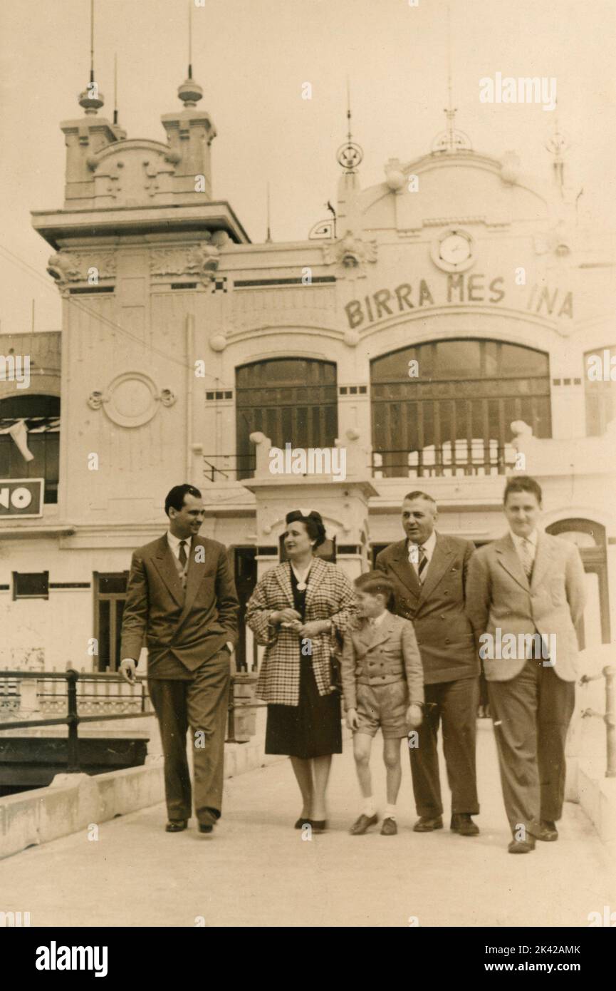 Familie beim Spaziergang vor dem Badehaus Mondello mit Werbung für das Bier Birra Messina, Palermo, Italien 1954 Stockfoto