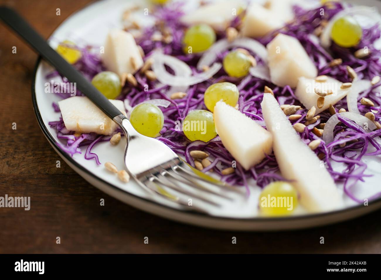 Hausgemachten gesunden Rotkohlsalat mit Birnen und Trauben auf einem Teller. Stockfoto