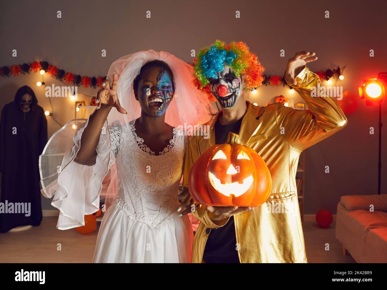 Zwei glückliche Erwachsene Freunde, die in Halloween-Kostümen von Dead Bride und Crazy Clown gekleidet sind Stockfoto