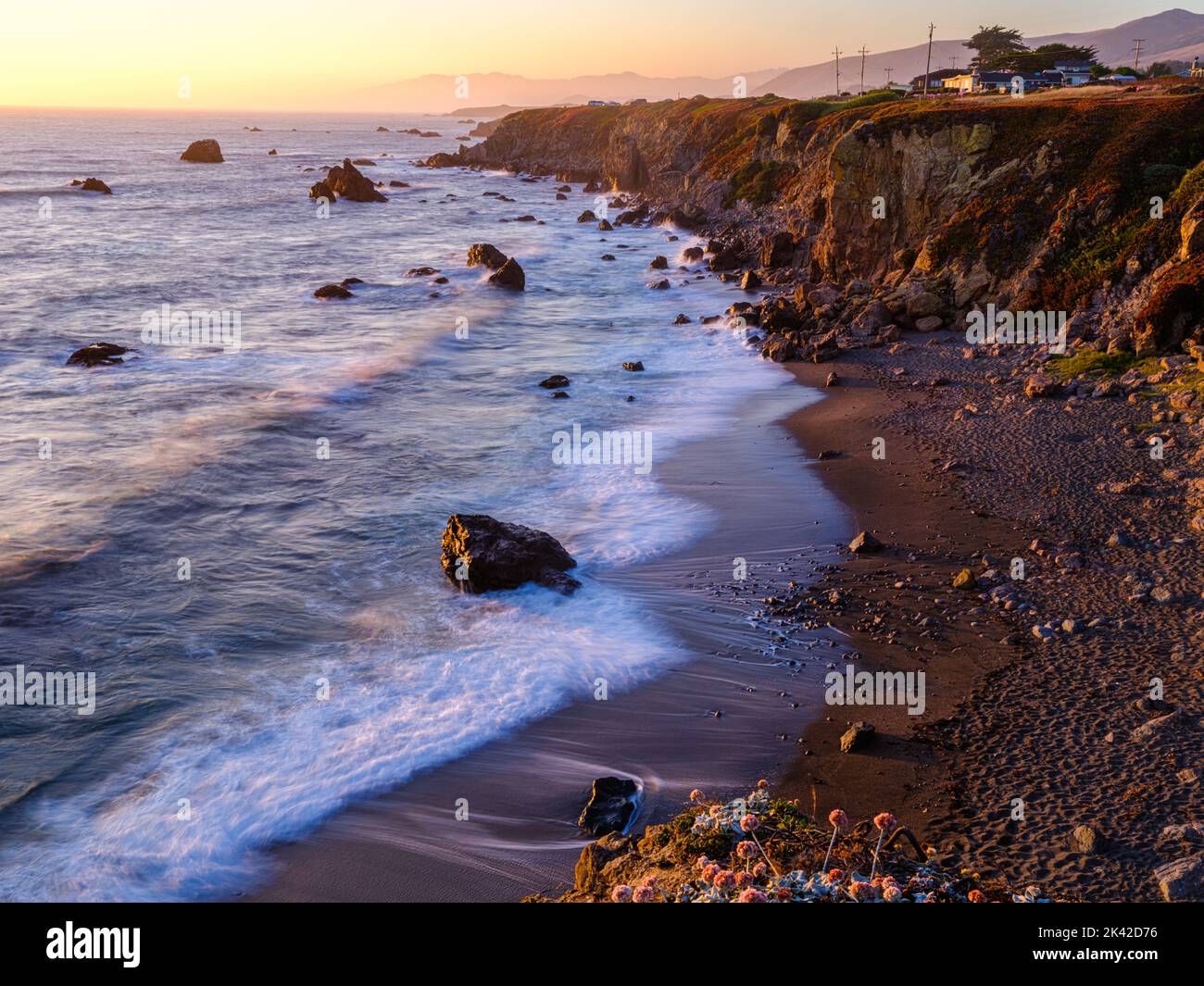 Ein romantischer Blick entlang der Küste der Bucht von Bodgea; sonnenverwöhnte Wellen bei Sonnenuntergang. Stockfoto