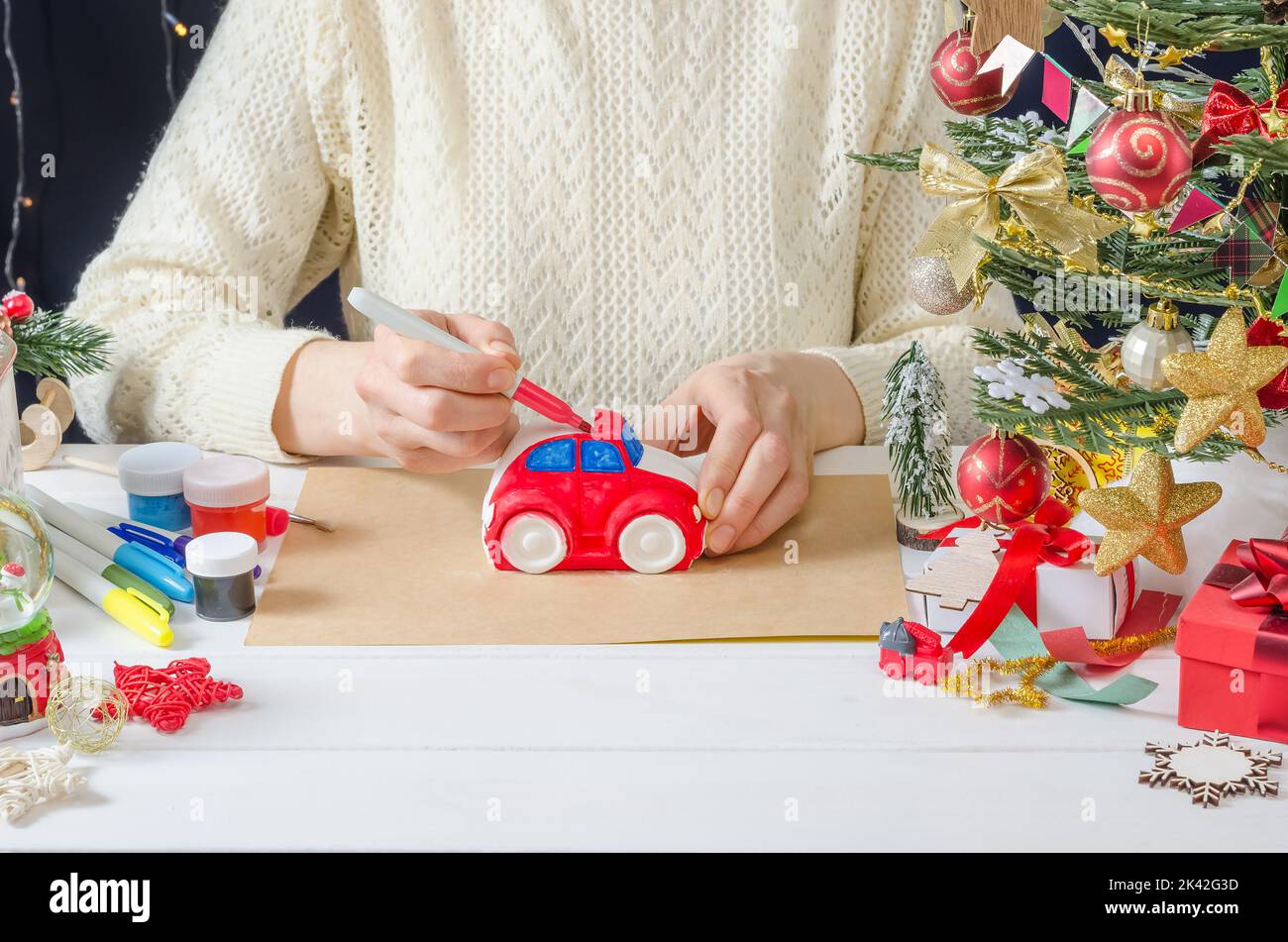 Schritt-für-Schritt Foto-Anleitung für Weihnachten Dekor - ein Mädchen malt eine Gipsmaschine, Schritt 3 - Färben des Körpers mit einem Filzstift Stockfoto