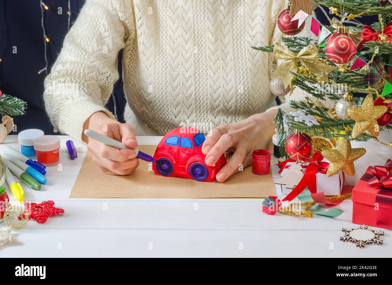 Schritt-für-Schritt Foto-Anleitung für Weihnachten Dekor - ein Mädchen malt eine Gipsmaschine, Schritt 5 - Färbung der Räder mit einem Filzstift Stockfoto