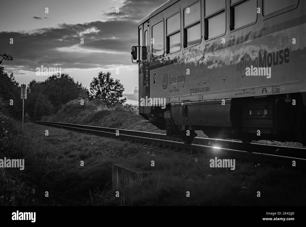 Tschechischer alter Personenzug mit orangefarbenem Sonnenuntergang in der Nähe der Stadt Rakovnik in Mittelböhmen Stockfoto