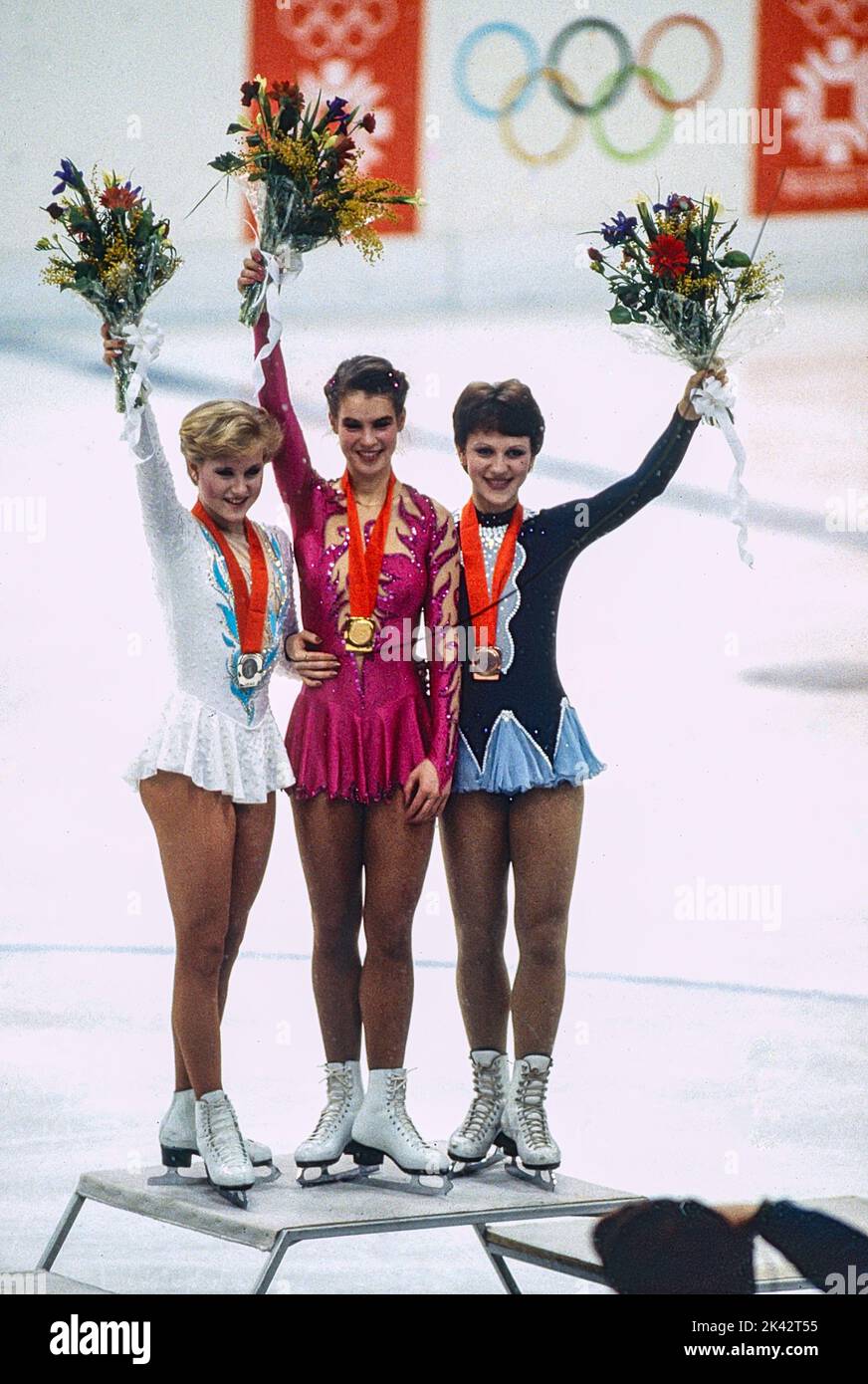 L-R Rosalynn Sumners (USA), Katarina Witt (DDR), Kira Ivanova (URS) Eiskunstlauf-Einzelmedaillengewinnerin der Damen bei den Olympischen Winterspielen 1984. Stockfoto
