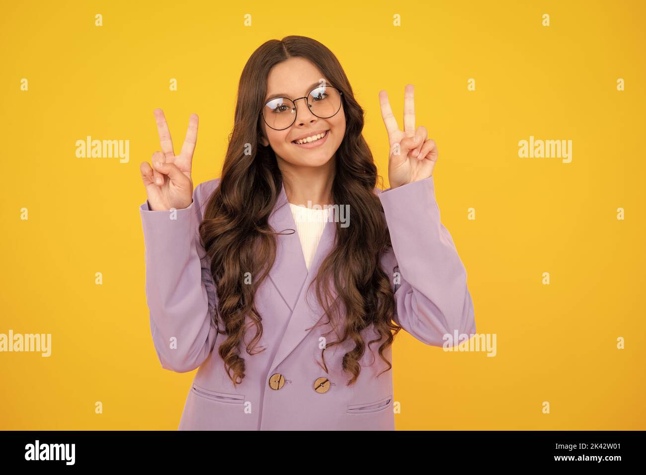 Lustige Teenager Kind Mädchen zeigen Frieden cool V-Zeichen isoliert auf gelbem Hintergrund. Stockfoto