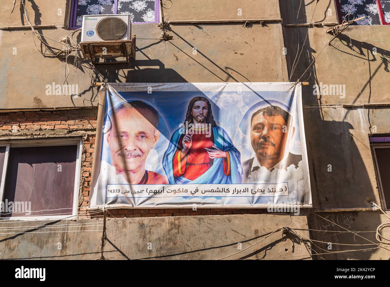 Manshiyat Naser, Garbage City, Kairo, Ägypten. 14. Februar 2022. Plakat koptischer christlicher Führer und Jesu, mit biblischen Versen in arabischer Sprache in Manshiy Stockfoto