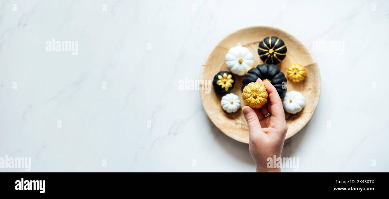 Dekorieren von Kürbissen-Ideen. Trending Malerei Schwarz Gold Weiß Kürbis in runden Teller. Minimal Draufsicht flach Lay Herbst Komposition mit Malerei schwarz Stockfoto
