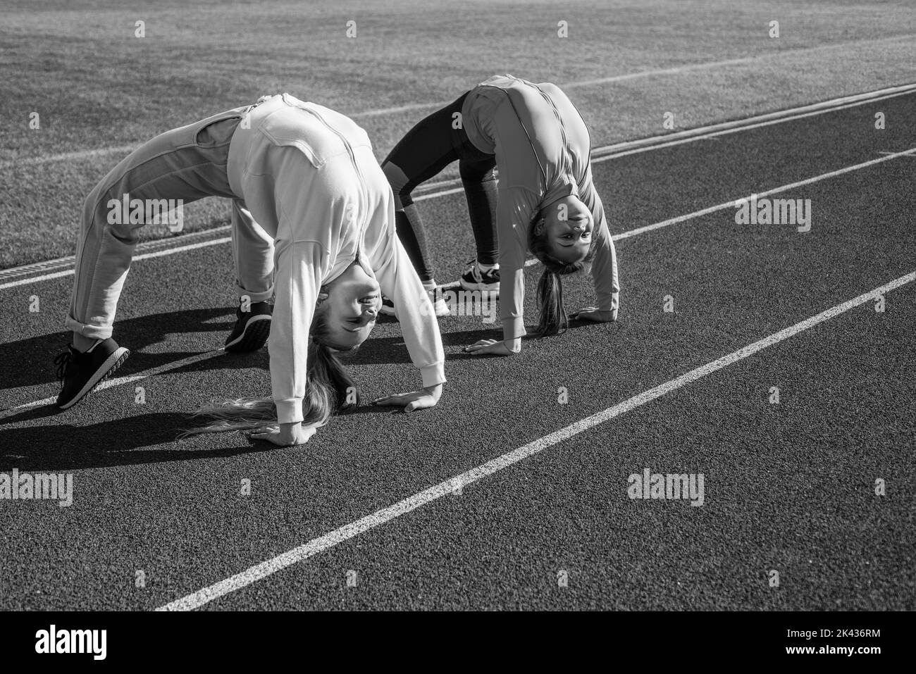 Flexible Mädchen Turnerinnen stehen in Krabbenposition auf der Leichtathletik-Strecke, Flexibilität Stockfoto