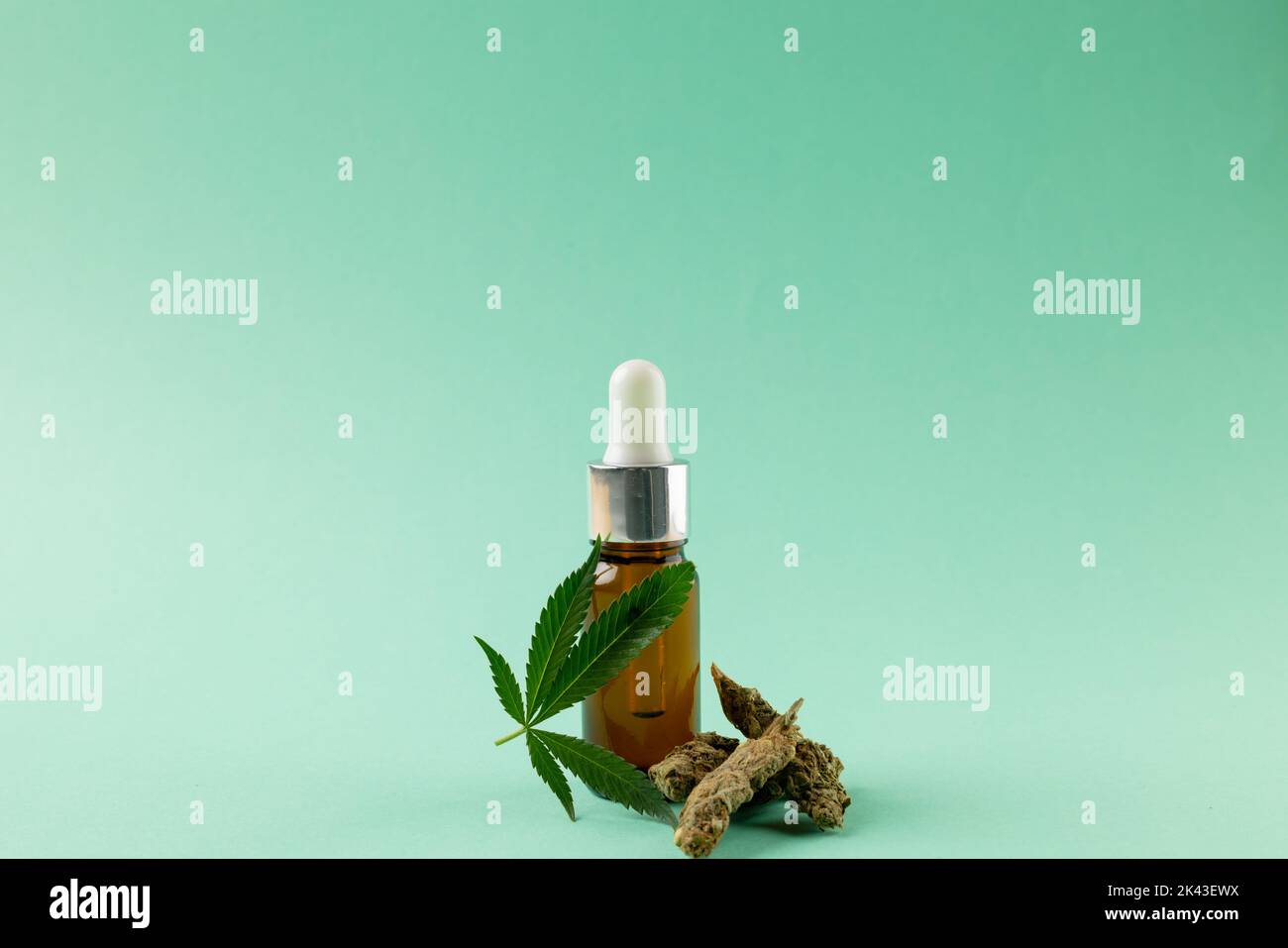 Bild einer Flasche CBD-Öl und getrockneten Marihuana-Blättern auf grüner Oberfläche Stockfoto
