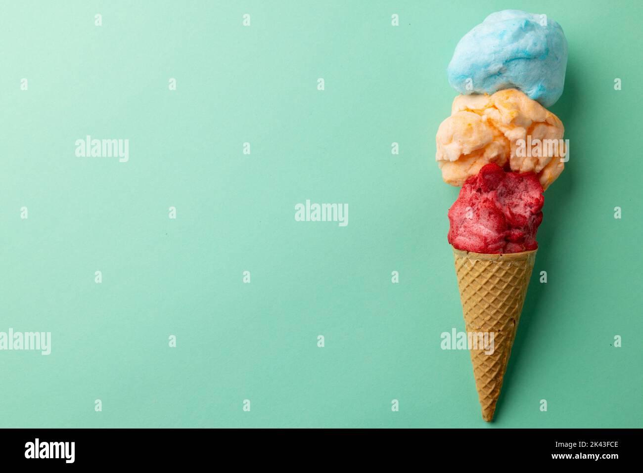 Horizontales Bild von drei farbigen Geschmacksrichtungen von Eis in Kegel, auf blauem Hintergrund mit Kopierraum Stockfoto