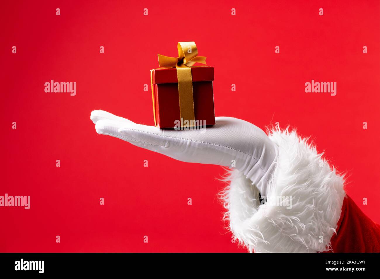 Bild der Hand des weihnachtsmannes mit weihnachtsgeschenk mit Kopierplatz auf rotem Hintergrund Stockfoto