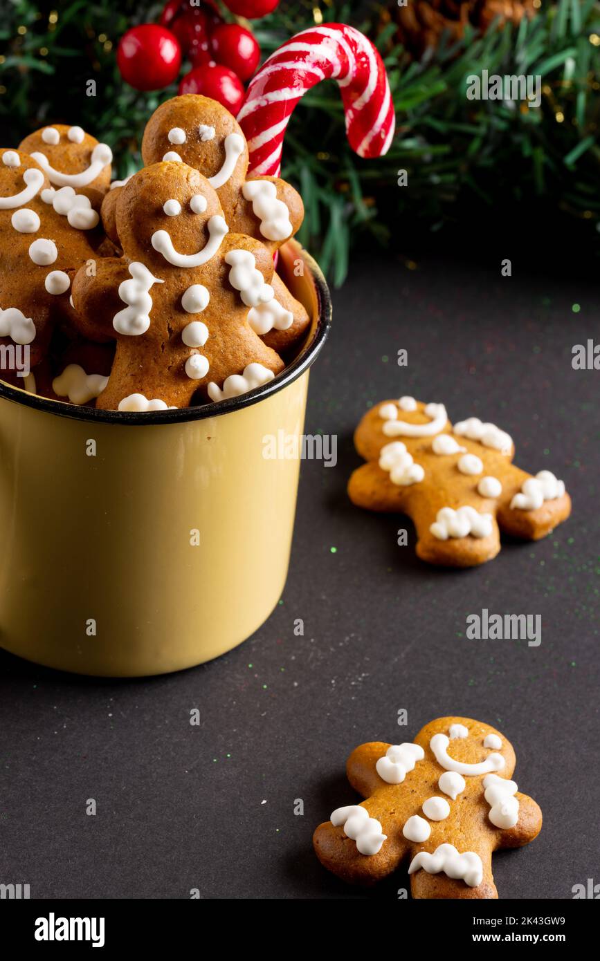 Bild von gelben Becher mit weihnachten Lebkuchenmänner und Zuckerrohr auf schwarzem Hintergrund Stockfoto