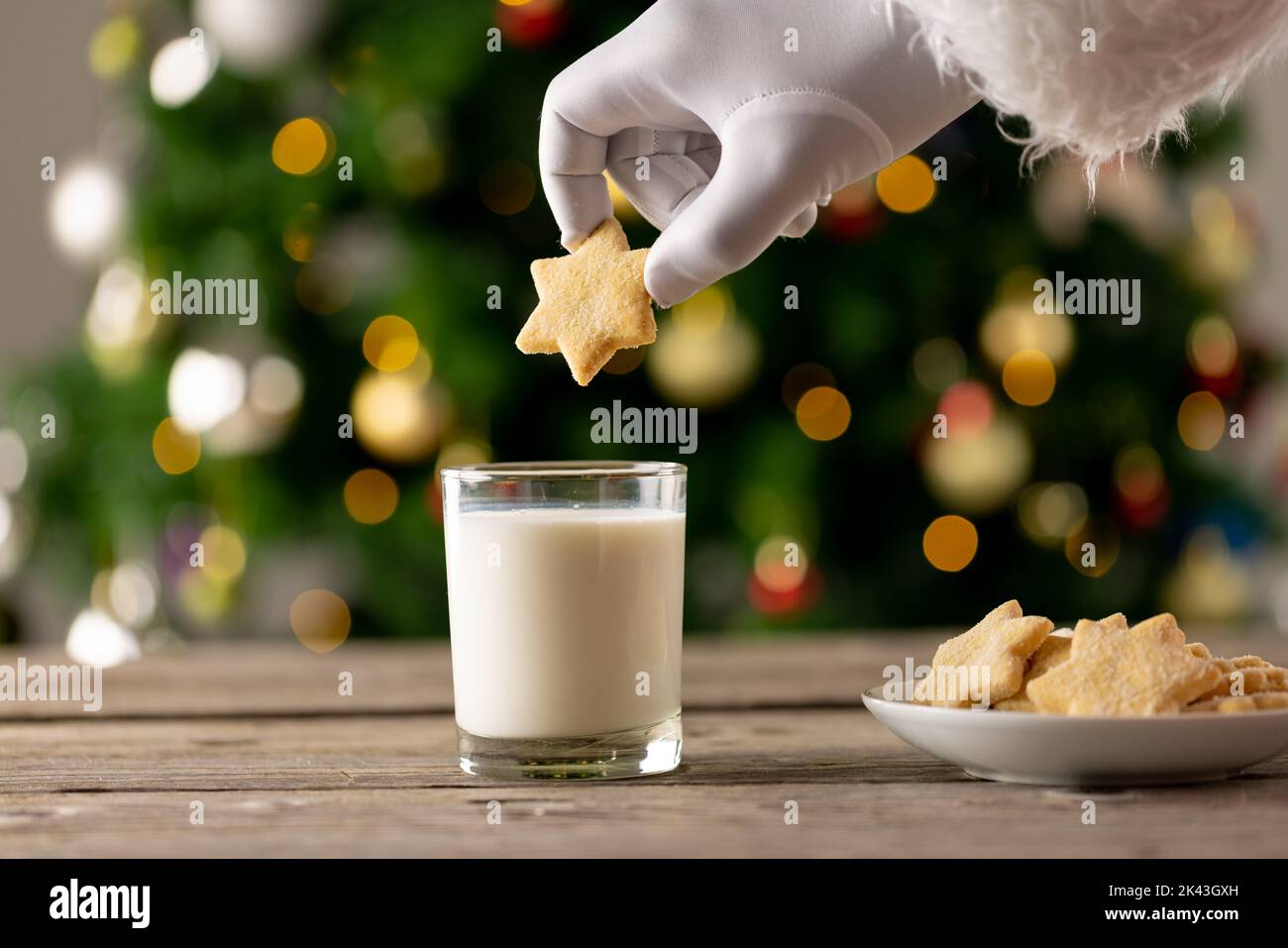 Bild der Hand des weihnachtsmanns, der den Weihnachtsstern über ein Glas Milch hält Stockfoto