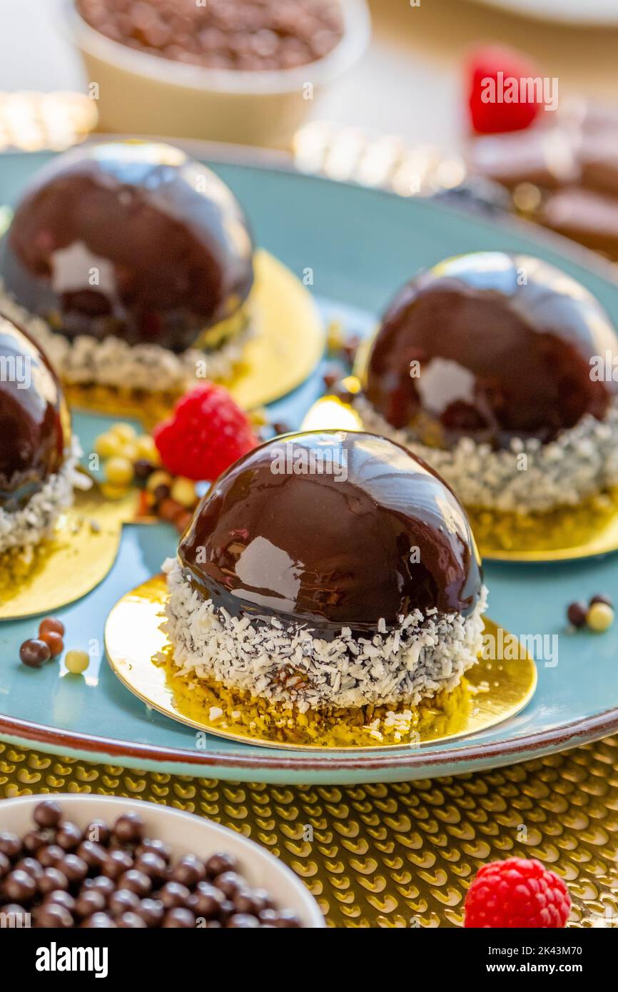 Schokoladenkuchen mit Himbeere auf einem blauen Teller und Schokoladendekor auf einem beigen Tisch.Beerendessert.zarte, luftige Kuchensouffle.appetitliche Cupcakes Stockfoto