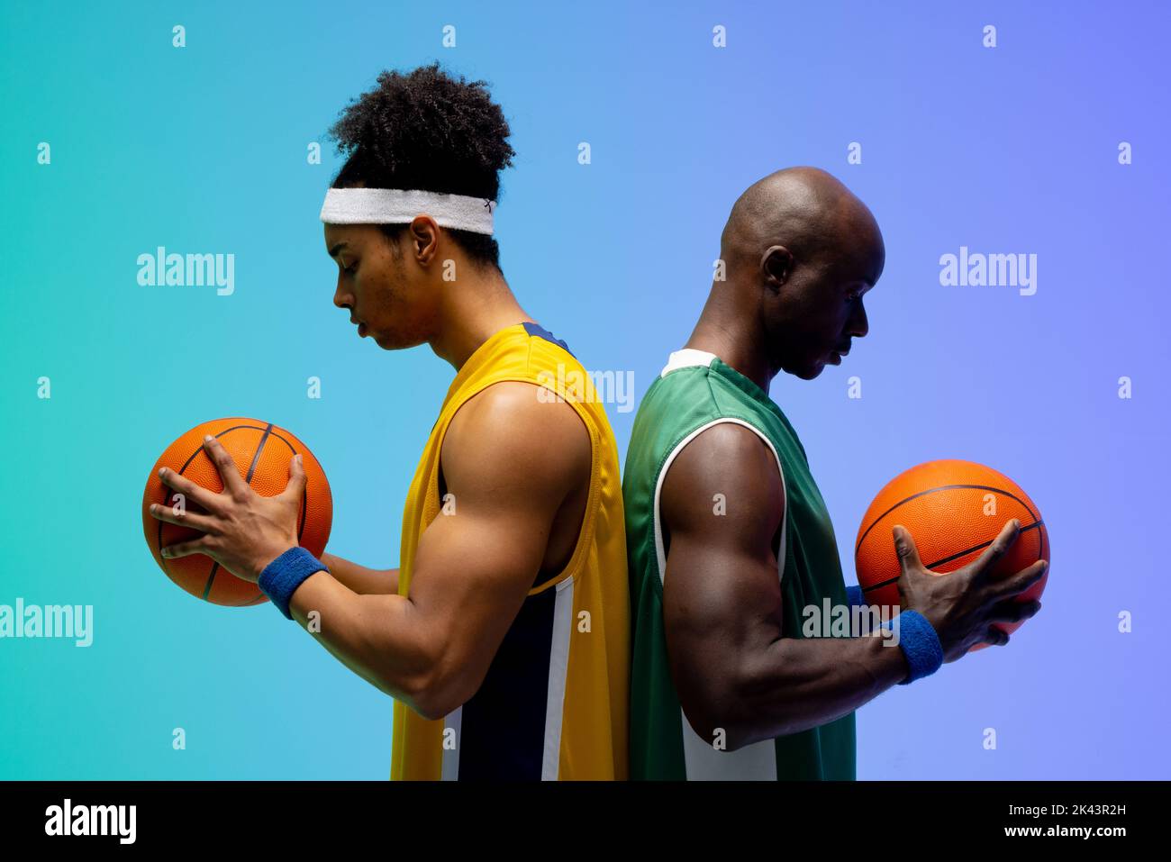 Bild von zwei verschiedenen Basketballspielern mit Basketballkörben auf violettem bis grünem Hintergrund Stockfoto
