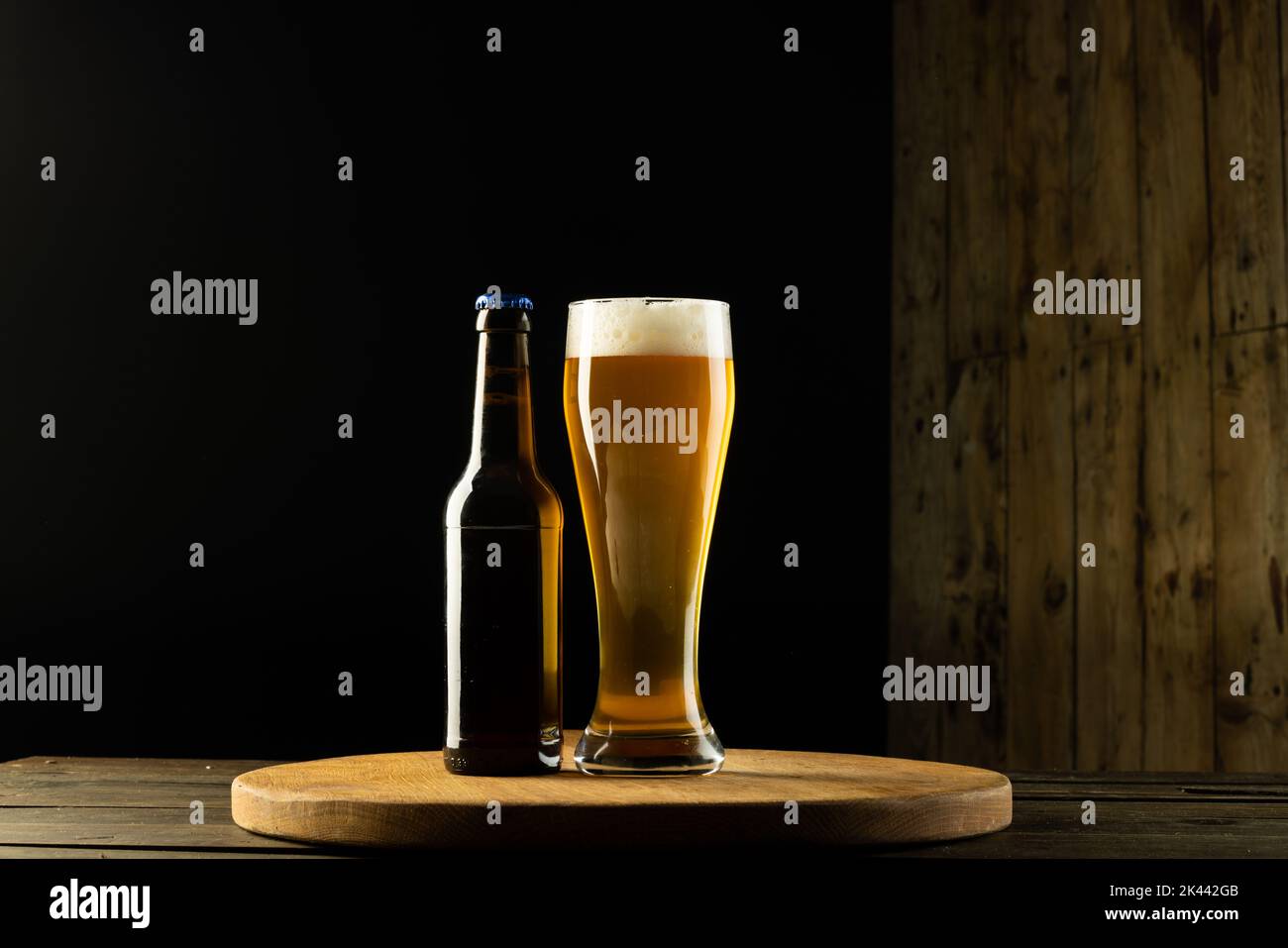 Bild einer vollen Flasche und eines Bierglases auf einem Holztisch mit Platz für Kopien Stockfoto