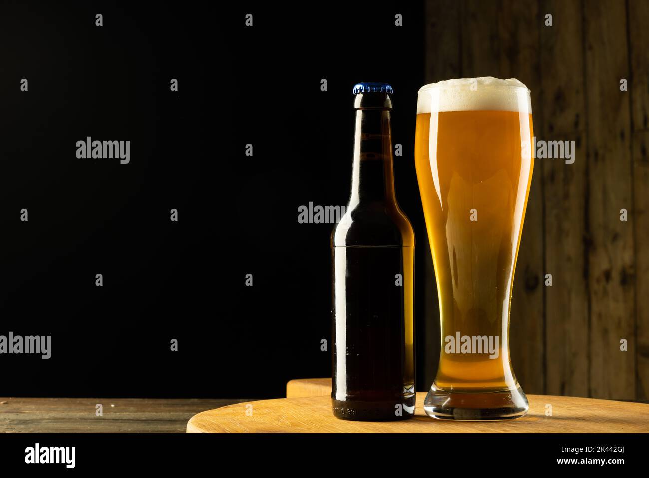 Bild einer vollen Flasche und eines Bierglases auf einem Holztisch mit Platz für Kopien Stockfoto
