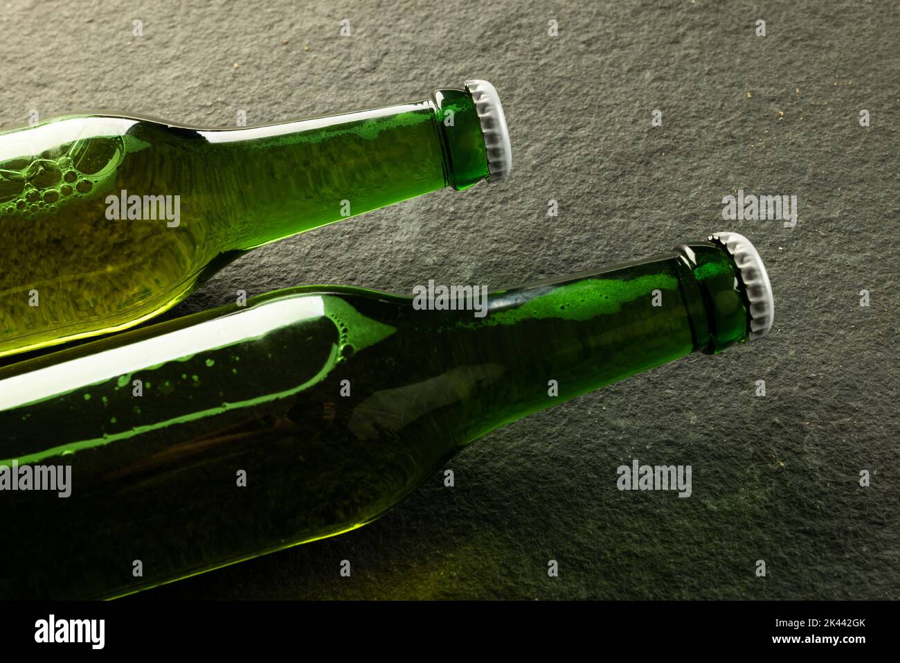 Bild von zwei grünen Bierflaschen aus Glas mit weißen Kronkorken auf Schiefer, mit Platz für Kopien Stockfoto