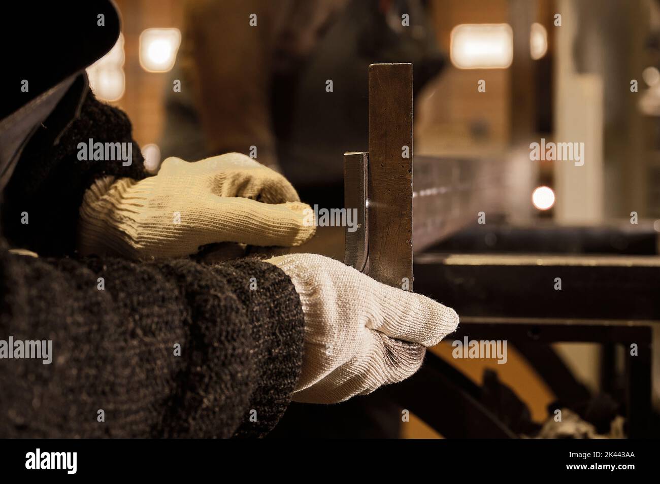 Der Arbeiter überprüft die Genauigkeit der Ecken von gebogenen Metalldetails mit Hilfe der Führung Stockfoto