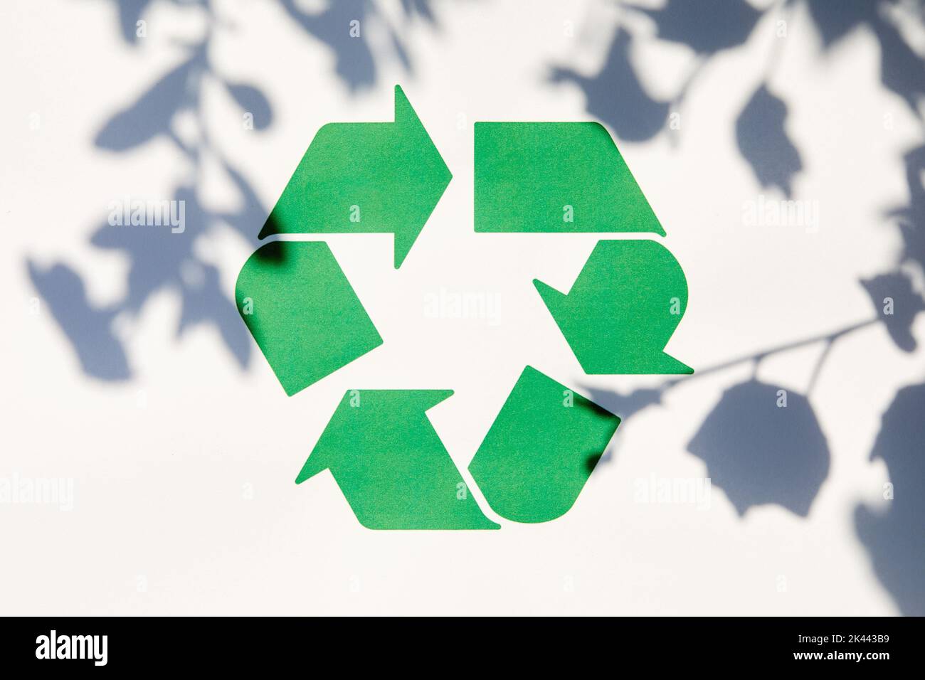 Grünes Recycling-Symbol an der weißen Wand mit Schatten Stockfoto