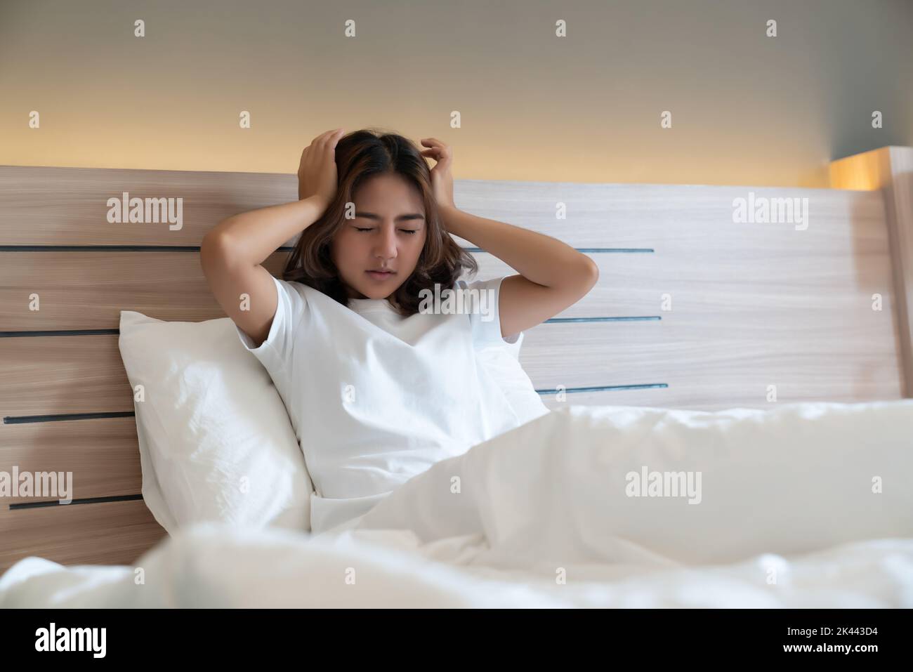 Junge asiatische Frauen liegen im Bett und halten ihren Kopf Ein starker Kopfschmerzen vielleicht Migräne am Morgen auf dem Bett Stockfoto