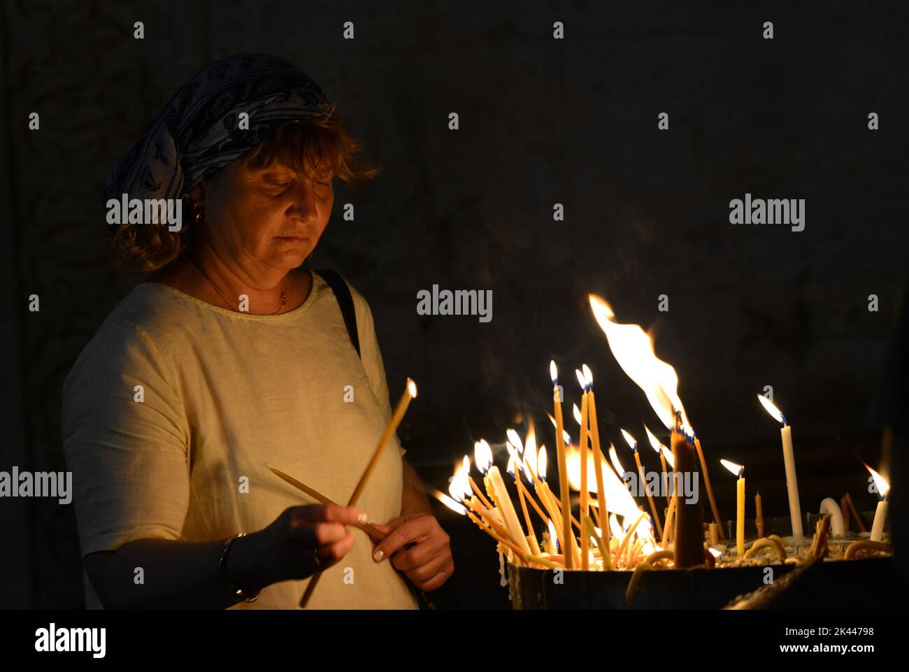 Eine Frau zündete Kerzen in der Kirche des heiligen Grabes in der Altstadt von Jerusalem, Israel. Stockfoto