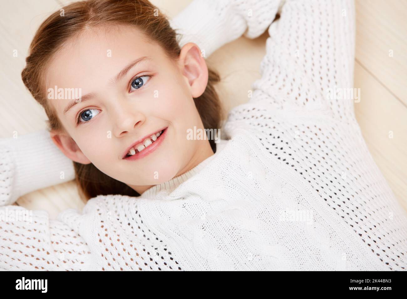 Einfach nur entspannend. Ein nettes kleines Mädchen lächelt, während sie zurückliegt und wegschaut. Stockfoto