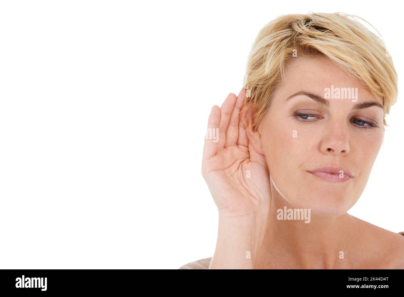 Können Sie es hören? Eine hübsche junge Frau mit einer Hand am Ohr, während sie auf weißem Hintergrund isoliert ist. Stockfoto