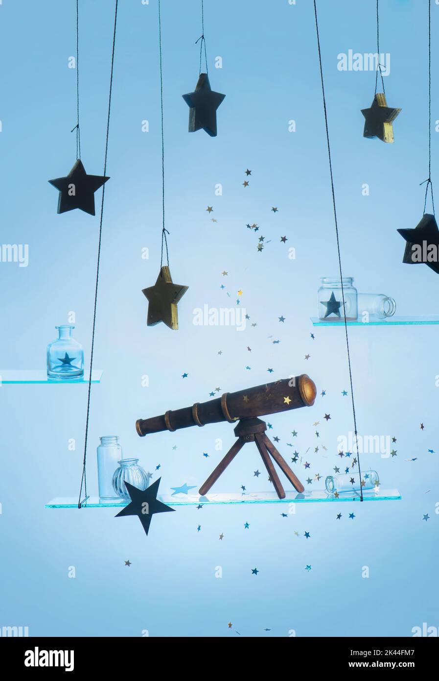 Spielzeug-Teleskop auf einem Glasregal mit Sternen, verträumtes Stillleben über Astronomie Stockfoto