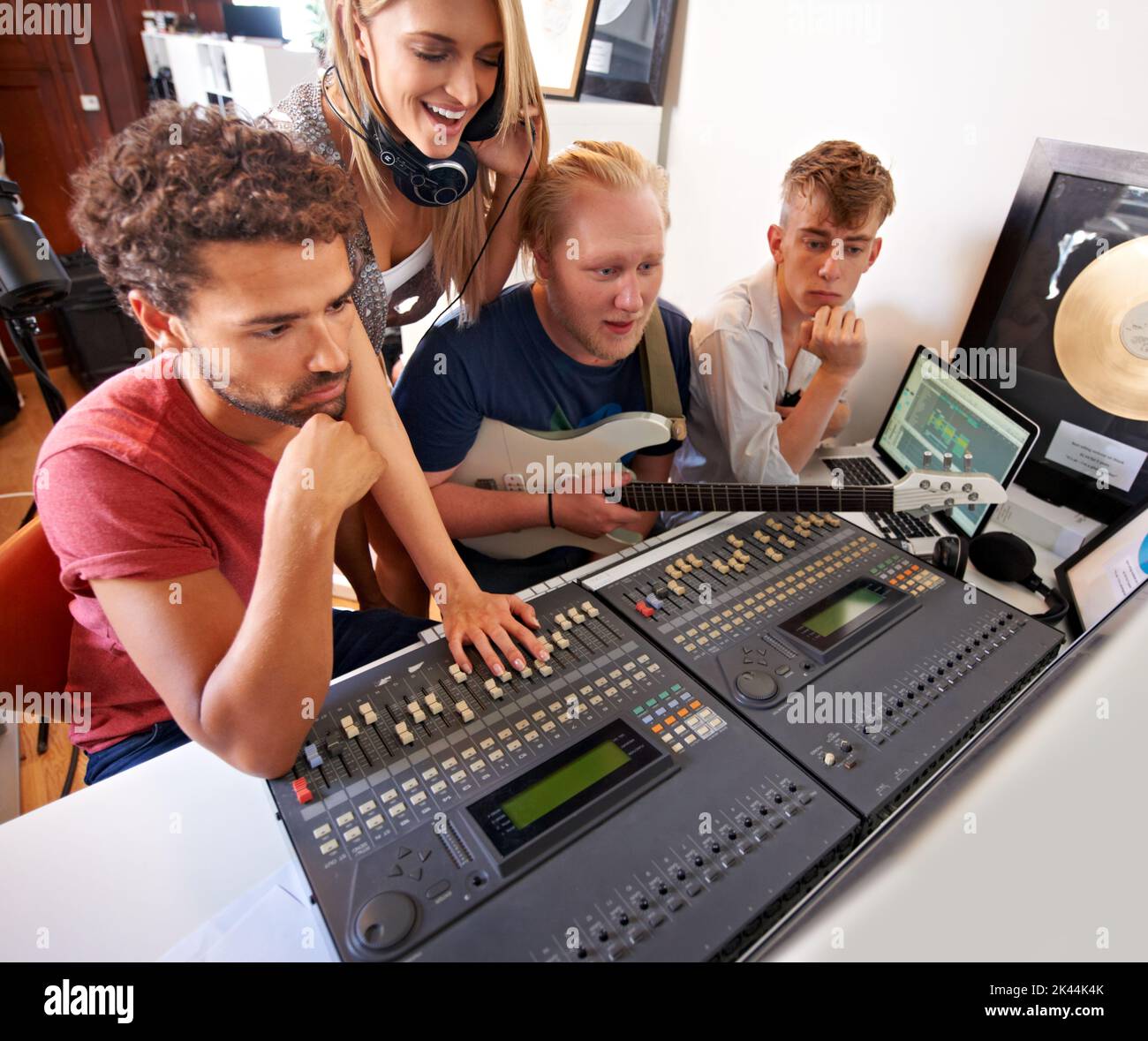 Lassen Sie es sich anhören... vier junge Musikproduzenten sitzen in ihrem Studio vor einem Mischpult. Stockfoto