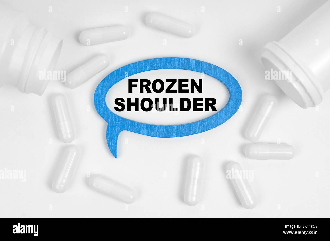 Medizinkonzept. Auf dem Tisch befinden sich Pillen und eine blaue Plakette, in der die Inschrift - Frozen Shoulder Stockfoto