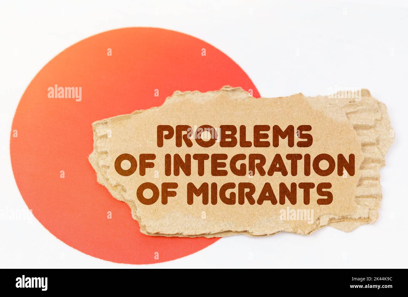 Politik und Menschen Konzept. Auf der Flagge Japans liegt ein Notizbuch mit der Aufschrift - Probleme der Integration von Migranten Stockfoto
