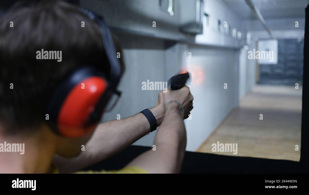 Schütze Mann hält Waffe in der Hand und schießt auf ein Ziel Rückansicht Stockfoto