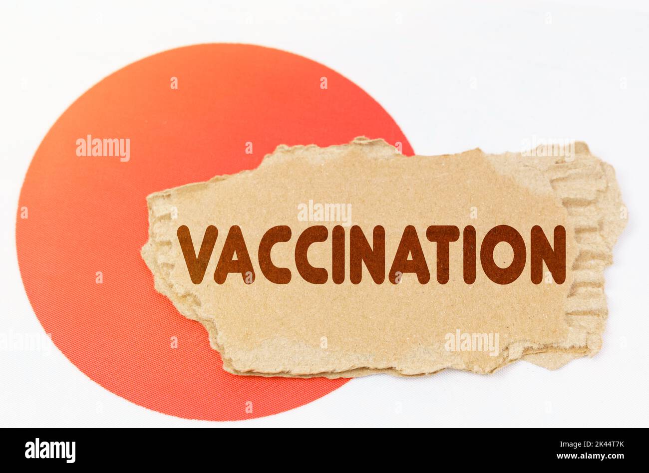 Konzept der nationalen Medizin. Auf der Flagge Japans liegt ein Notizbuch mit der Aufschrift - IMPFUNG Stockfoto