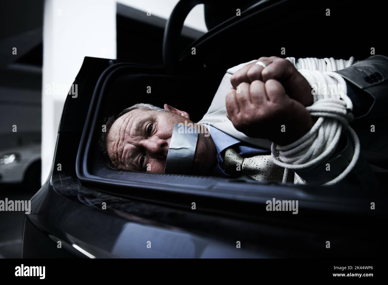 Gebunden und geknebelt. Ein verängstigter Geschäftsmann lag gebunden und geknebelt im Kofferraum seines Autos. Stockfoto