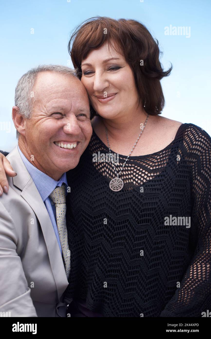 Sie erfüllen sich gegenseitig Leben. Eine reife Frau, die auf dem Schoß ihres Mannes sitzt und glücklich lächelt. Stockfoto