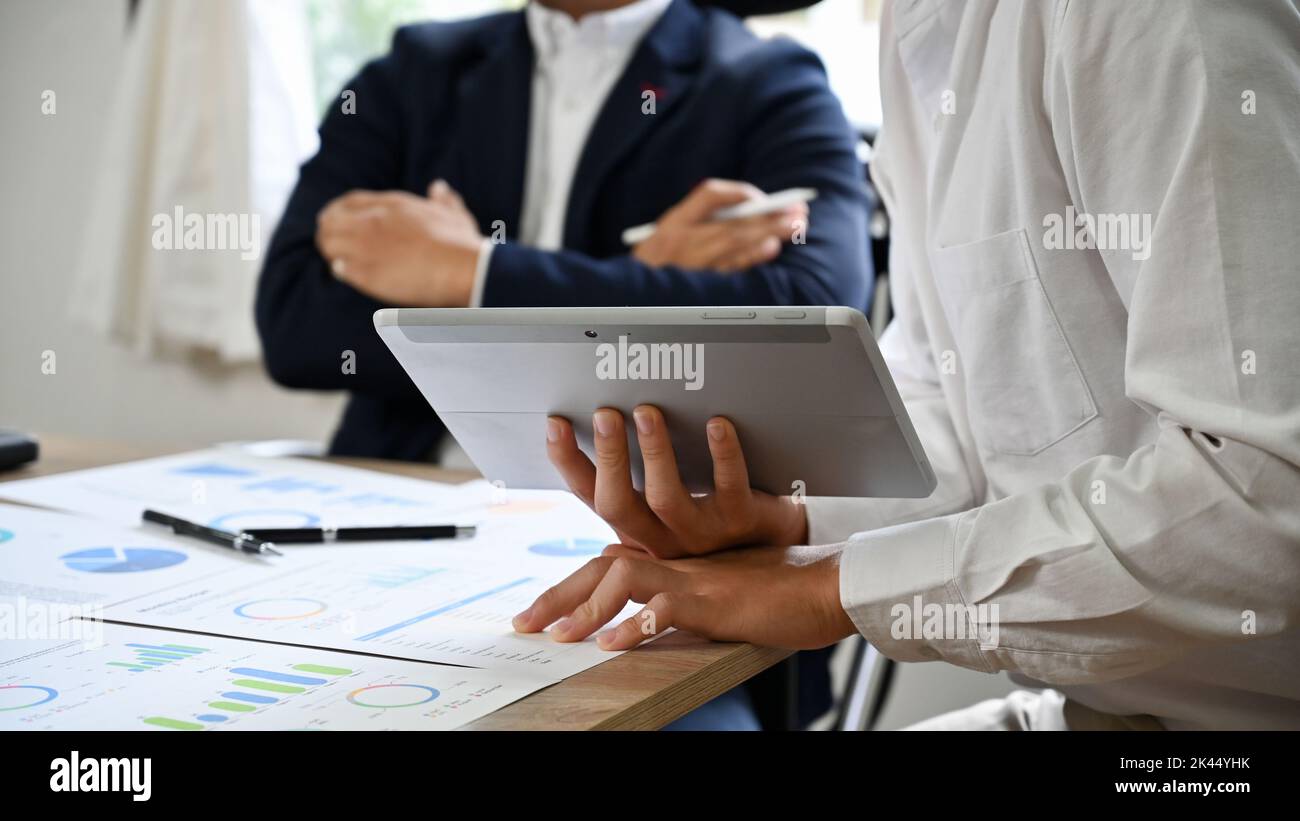Ein junger asiatischer Geschäftsmann oder Marketingmitarbeiter präsentiert und teilt seine Ideen mit den Vorstandsmitgliedern in der Sitzung. Zugeschnittenes Bild Stockfoto